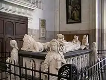 Un tombeau de marbre blanc richement sculpté, avec deux gisants.