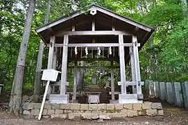 Photo couleur d'un hall ouvert en bois gris, entouré d'arbres.