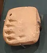 Petite tablette carrée avec des signes ronds et linéaires.