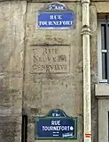Ancien nom de la rue entre deux plaques récentes ; le « Ste » de Geneviève a été martelé à la Révolution.