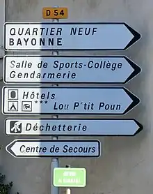 Cinq panneaux D21b avec trois idéogrammes réglementaires (ID8, ID9, ID24), et deux non.