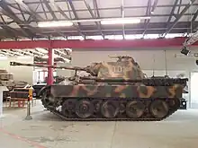 Photographie prise dans un musée montrant un char Panther vu de profil ; il est peint en couleur camouflage et porte le numéro II01 en rouge sur la tourelle.