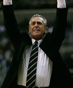 Pat Riley, en costume, les bras en l'air.