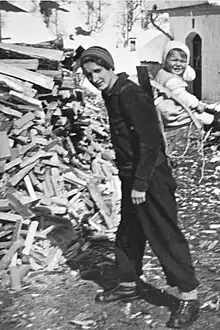 Greti Caprez-Roffler portant son enfant sur le dos au moyen d'une chaise portable.