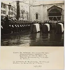 Photo noir et blanc (avec une légende) : au centre trois cercueils recouverts d'un drapeau, à gauche des hommes en uniforme avec casques et gants blancs, au fond des officiels.
