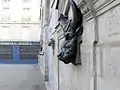 Ancienne bouche de fontaine en forme de tête, ornant la façade de l'école.