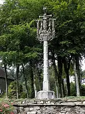 Photographie d'un calvaire en granite avec des arbres derrière
