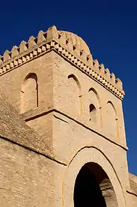 Photographie de la partie supérieure du quatrième porche de la façade occidentale. Elle est décorée d'arcatures aveugles brisées. L'arcature médiane de la façade antérieure est percée d'une petite baie.