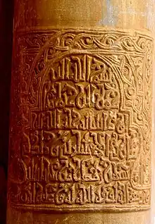 Gros plan sur une inscription coufique en relief, datée de 1011, gravée sur le fût d'une colonne de la façade du portique occidental.