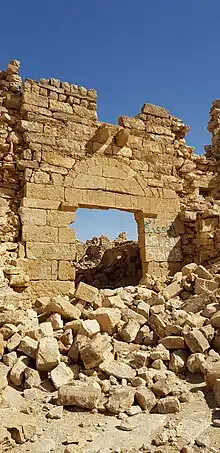 porte dans un mur de pierres blondes en ruine