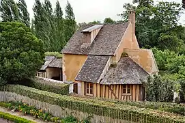 Réchauffoir au hameau de la Reine ; Petit Trianon, parc ; ce hameau d'agrément est commandé durant l'hiver 1782–1783 par la reine Marie-Antoinette, souhaitant s'éloigner des contraintes de la cour de Versailles, avec la nostalgie d'une vie plus rustique, dans un décor de nature inspiré par les écrits de Rousseau.