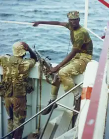 Photographie de deux hommes noirs en uniformes militaires avec un mitrailleuse sur le pont d'un navire