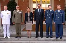 Femme entourée de cinq hommes, dont quatre vêtus d'uniformes militaires.