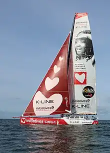 Voilier rouge et blanc en mer, vu en entier, de profil.