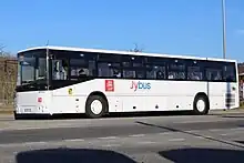Photographie en couleurs d’un un autocar blanc et noir avec les logos de la communauté de communes Rumilly Terre de Savoie et du réseau J’ybus sur le côté et sur la face avant.