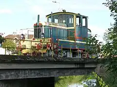 Photohraphie d'un locotracteur en livrée vert sombre et bandes jaunes.