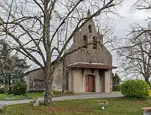 Photo de l'église Saint-Pierre. Vue de la porte d'entrée, située sur le clocher-mur et protégé par un porche. L'édifice est une église à nef unique.