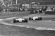Photo en noir et blanc de deux monoplaces sur un circuit.