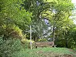 Une croix en fer forgé et un banc placé sur le chemin