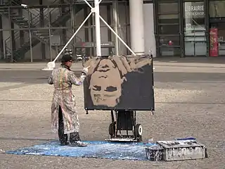 Artiste peignant un portrait à l'envers sur la place.