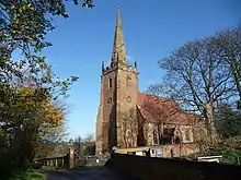 Photo d'un bâtiment avec une grande tour carrée au toit crénelé et coiffé d'une haute flèche
