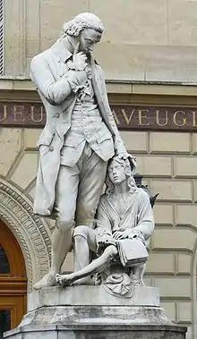 Statue représentant Valentin Haüy, réalisée par Badiou de la Tronchère. Elle est située à l'Institut des jeunes aveugles à Paris. Valentin Haüy semble pensif, la main droite sur la tempe, la main gauche posée affectueusement sur un jeune aveugle assis à ses pieds, qui est en train de lire un livre en braille.