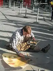 Un artiste de rue (un madonnaro) à l’œuvre piazza Beaubourg (2005), reproduisant au sol La Jeune Fille à la perle de Vermeer de Delft.