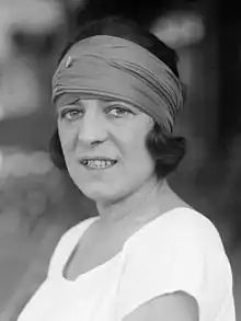 Portrait photographique de Suzanne Lenglen portant un t-shirt blanc et un foulard sur la tête.