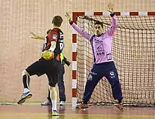 Photo d'un gardien de handball subissant un tir.