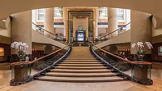 Vue symétrique de l'escalier de l'hôtel The Fullerton, Singapour, avec des rampes décorées de bouquets de fleurs. Juin 2018.