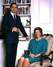 Portrait d'un homme (debout) et d'une femme (assise) devant une bibliothèque.