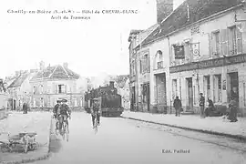 La route de Paris avec la façade de l'auberge à droite, photographiée pour une carte postale au tournant du XXe&nbsp;siècle.