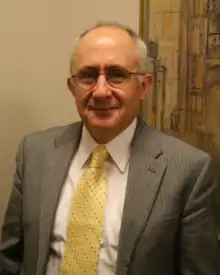 Photographie d'un homme portant un costume cravate et des lunettes.