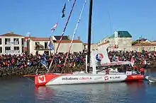 Voilier blanc et rouge, vu de profil, avançant dans le chenal des Sables-d'Olonne.
