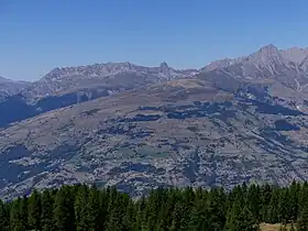 La Pierra Menta encadrée par la Grande Paréi à gauche et le Roignais à droite avec devant eux le dôme de Vaugelaz depuis Peisey-Vallandry de l'autre côté de la vallée de la Tarentaise au sud-est.