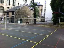 Photographie des terrains de sport du lycée Molière, et, au fond, une des façades du lycée et des bâtiments annexes.