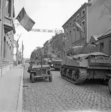 Dans une rue d’Antoing, le 3 septembre 1944, chars Sherman de la 5e division blindée des Gardes de l’armée de terre du Royaume-Uni croisant une jeep américaine durant les opérations de libération de la Belgique.