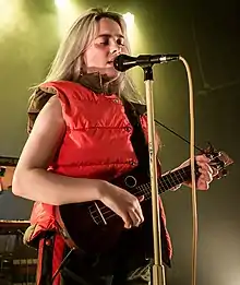 Photo d'une femme qui joue du hukulélé tout en chantant.