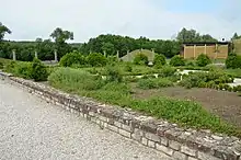 Vue d'un jardin avec à l'arrière-plan une colonnade et des tumulus.