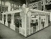 Un stand d'exposition à l'intérieur duquel on voit des meubles-vitrines et des lampes tout autour.