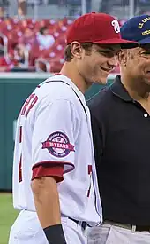 Un jeune joueur de baseball en tenue blanche portant une casquette rouge.