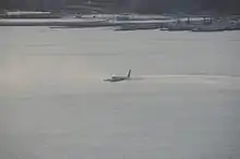 Photo de l'avion sur le fleuve, au centre de l'image, juste après l'amerrissage, avec la ville en arrière-plan.