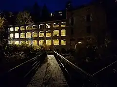 Photographie de l'ancienne usine du Faux-Martel éclairée de nuit en jaune.