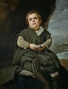 Un jeune homme (ou un enfant) assis, avec des vêtements amples faisant de nombreux plis.