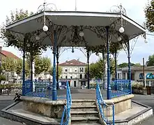 Le kiosque à musique sur la place de la Mairie où la scène du marché sous les arcades, avec Michel Serrault tenant un stand de vente de canard avec sa nouvelle famille gersoise dans le film Le bonheur est dans le pré, a été tournée.