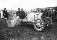 Photo d'une voiture moteur tournant dégageant un panache de fumée avec son pilote au volant.