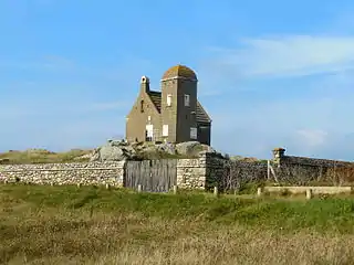 Vue d'un édifice néo-médiéval derrière un mur de pierres.