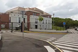 Vue d'un petit immeuble collectif dans une résidence ; alternance de panneaux pierre et brique.