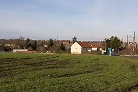 Vue d'un hameau en second plan ; zone agricole au premier plan.