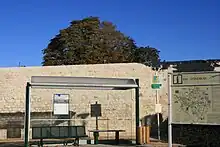 un arrêt de bus avec un mur en pierre derrière